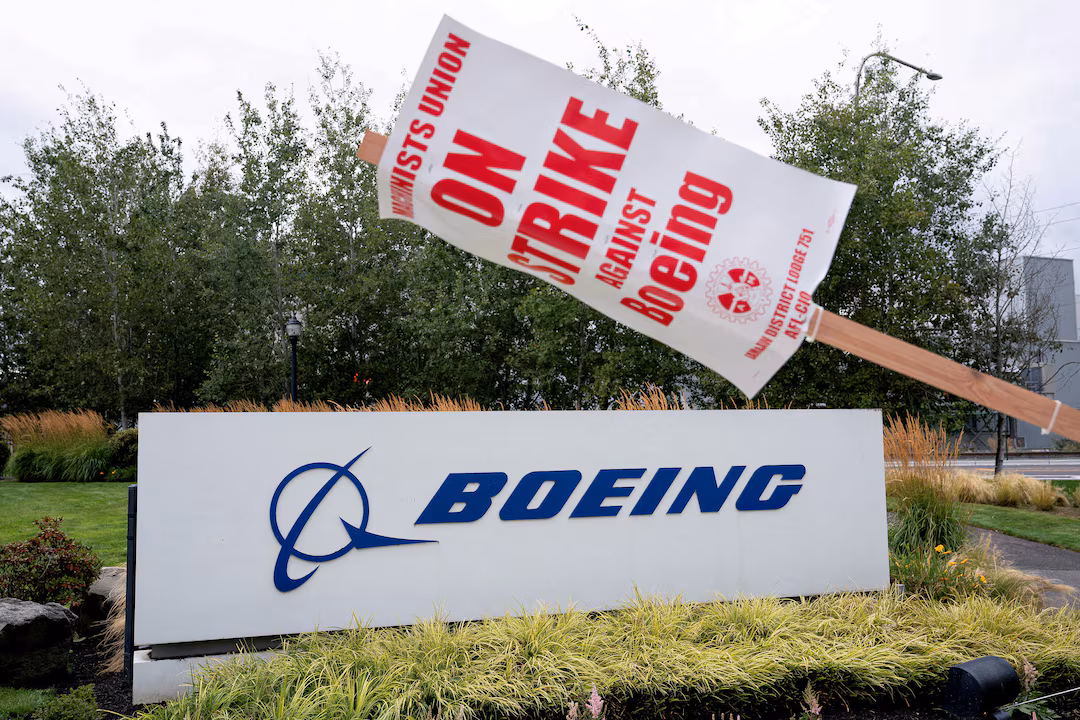 strike sign hangs from a post near a Boeing sign as Boeing factory workers and supporters gather on a picket line during the third day of a strike near the entrance to a Boeing production facility David Ryder
